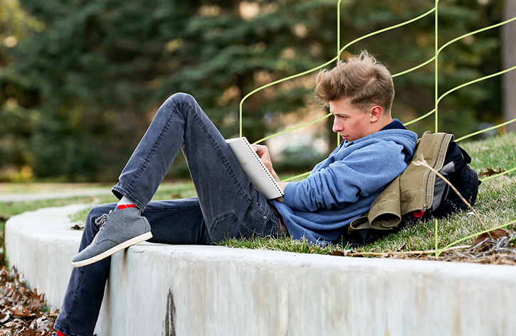 UW-Stout student reviews notes in outdoor space on campus.