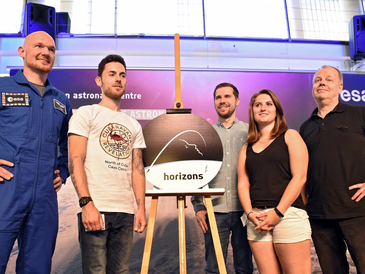 Megan Luedke takes part in a news conference to unveil the mission patch for German astronaut Alexander Gerst, left. Second from left is another student from the class, along with a class assistant and her professor, right.